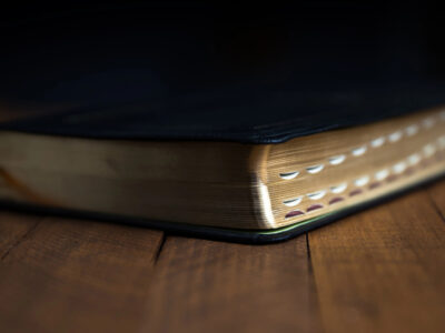 Black Bible with index tabs laying on dark wooden table