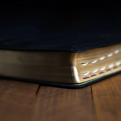 Black Bible with index tabs laying on dark wooden table
