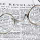 The book of Revelation in the Bible with old-fashioned glasses laying on top