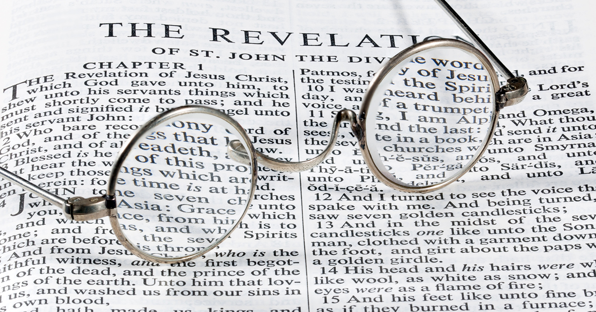 The book of Revelation in the Bible with old-fashioned glasses laying on top