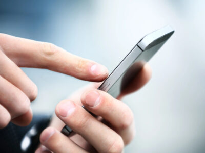 Man's hands dialing on a silver smart phone