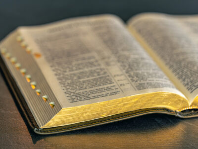 Open Bible with black cover and gold gilt edges on table